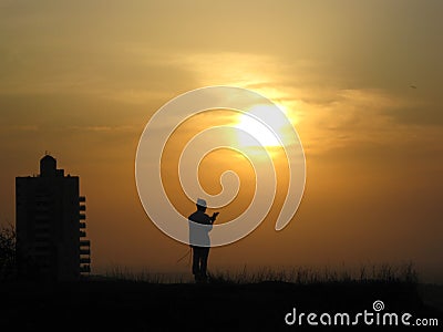 A religious person prays to God on a hill in front of the sun and sunset Stock Photo